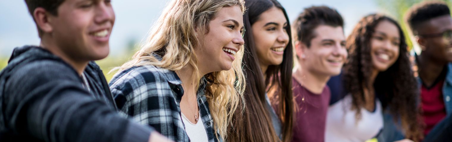 Six young people smiling in a row outside